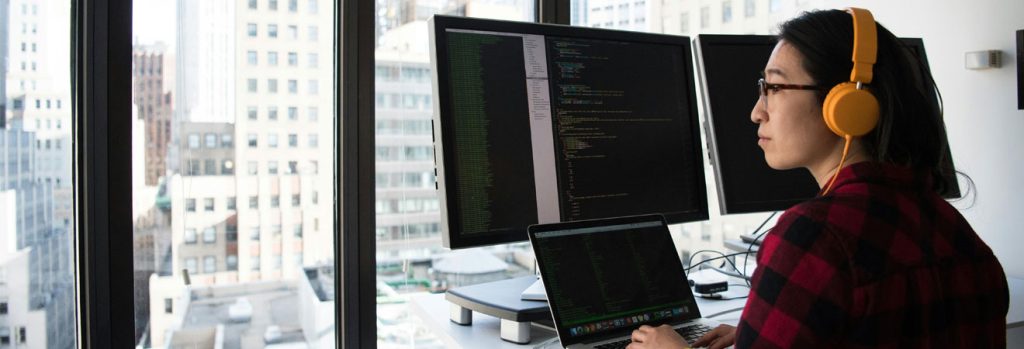 Professional working at dual monitors during IT office relocation setup