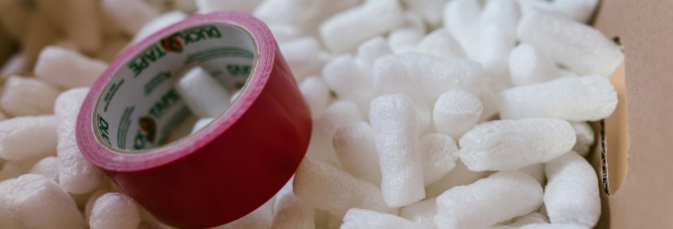 Red duct tape and packing peanuts inside a box.