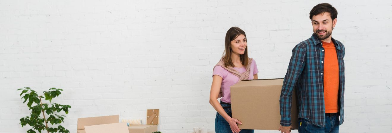 Woman carrying a moving box in a bright room, illustrating residential and office relocations handled by movers Deerfield Beach.