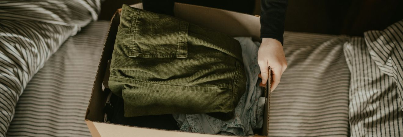 a person putting green jeans in a cardboard box