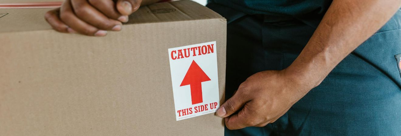 One of the movers North Lauderdale carrying a box with a fragile sign on it.