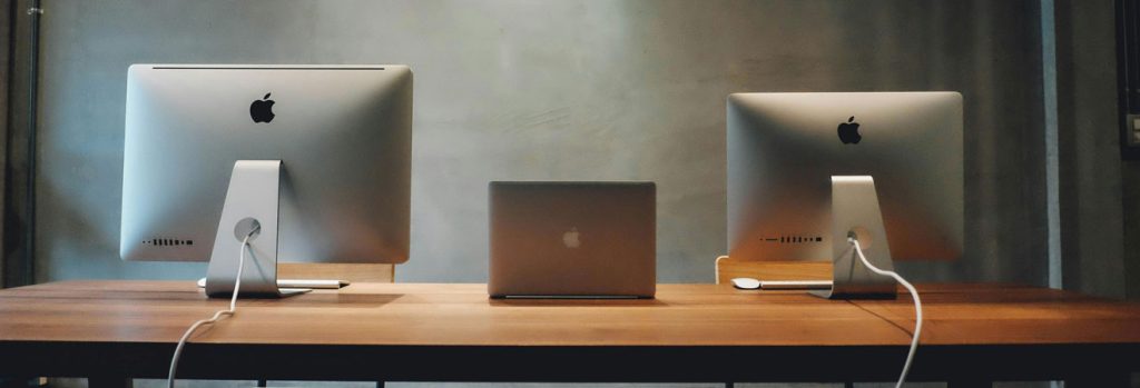 two iMacs and a MacBook in a minimalist workspace